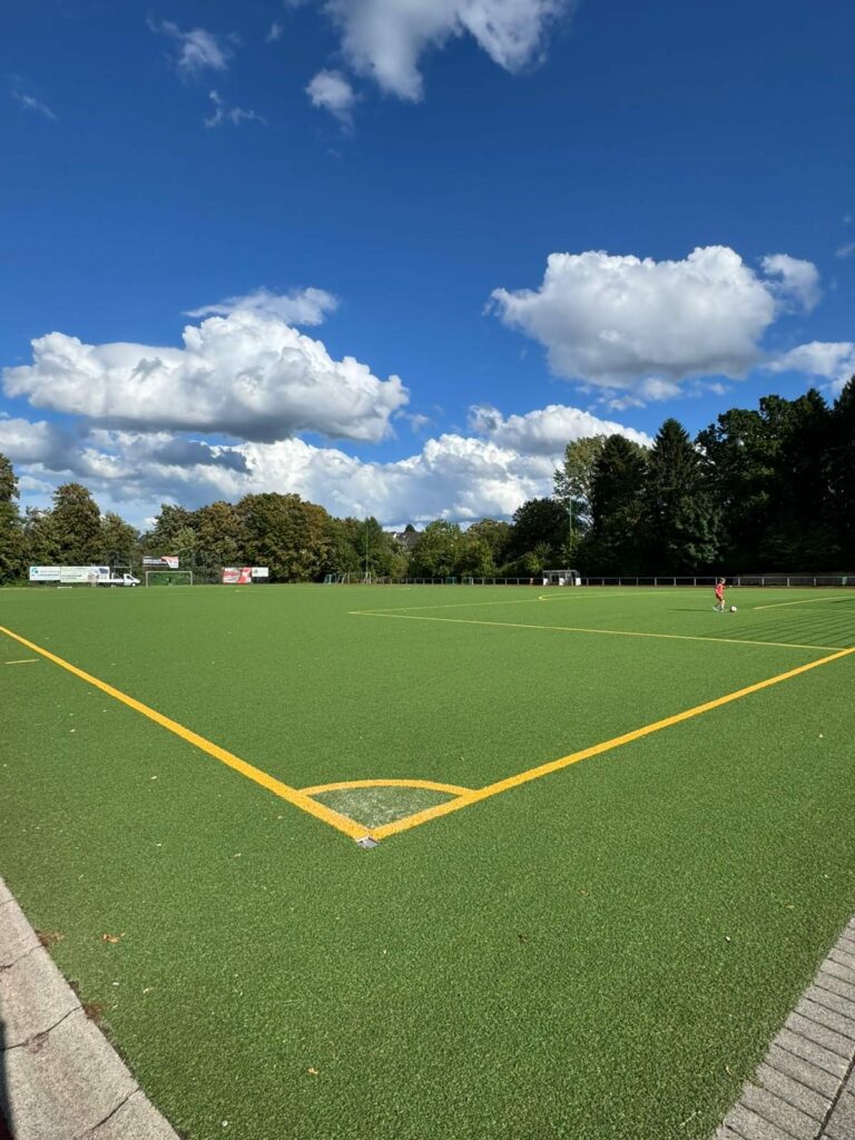 Kunstrasenplatz des BV Bergisch Neukirchen unter blauem Himmel