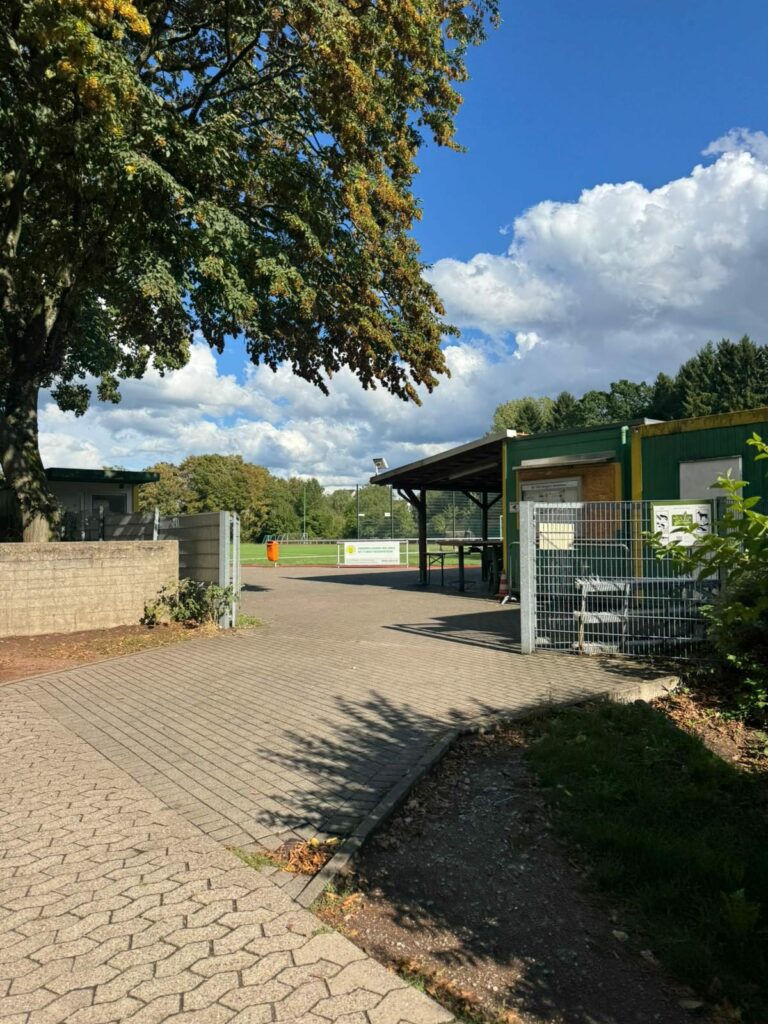Eingang zur Sportanlage mit Vereinsheim und Blick auf den Platz